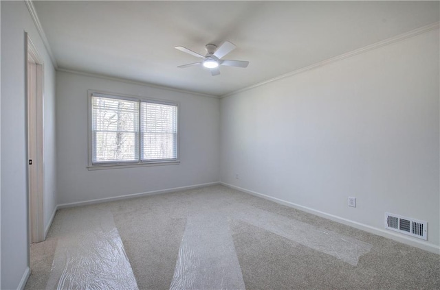 carpeted empty room with baseboards, visible vents, ceiling fan, and crown molding