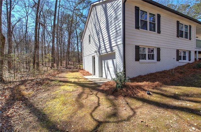 view of home's exterior with a garage, brick siding, and driveway