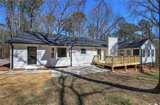 rear view of house with a deck, a patio area, and a chimney