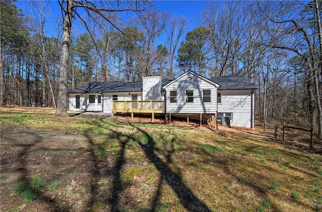 rear view of house featuring central AC unit, a deck, and a lawn