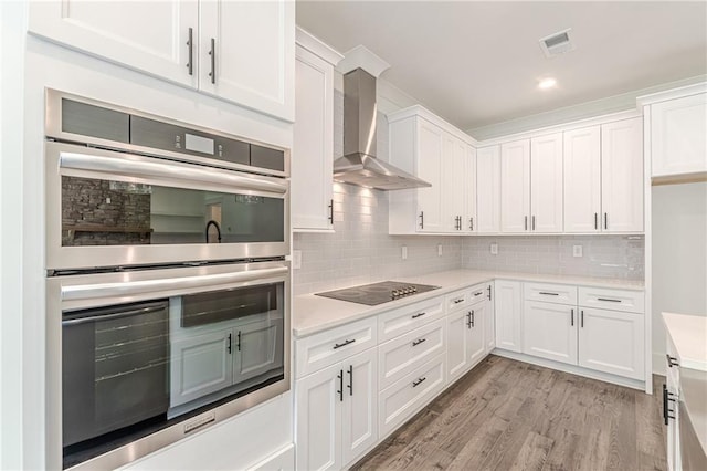 4075 O Henry Ct, Mcdonough, GA 30252 - kitchen with stainless steel double oven, black electric cooktop, wall chimney exhaust hood, light countertops, and white cabinetry