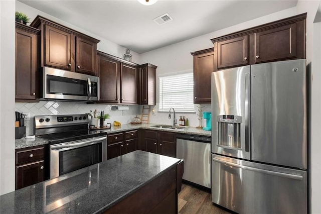 3406 Pennington Dr, Lithonia, GA 30038 - kitchen featuring stainless steel appliances, a sink, dark brown cabinets, and dark stone countertops