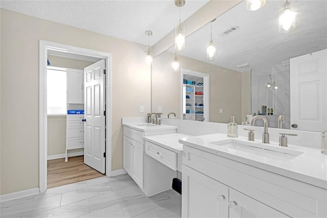 bathroom featuring vanity, a textured ceiling, and walk in shower