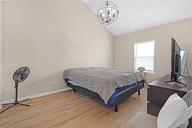 bedroom with lofted ceiling, an inviting chandelier, and light hardwood / wood-style floors