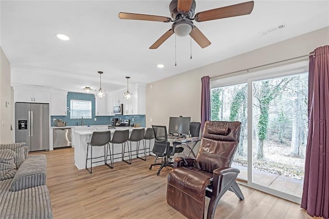 living room featuring ceiling fan, a healthy amount of sunlight, sink, and light wood-type flooring