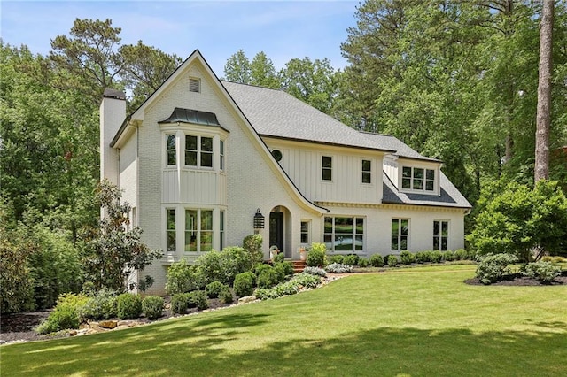 view of front of property featuring a chimney, a front lawn, and brick siding