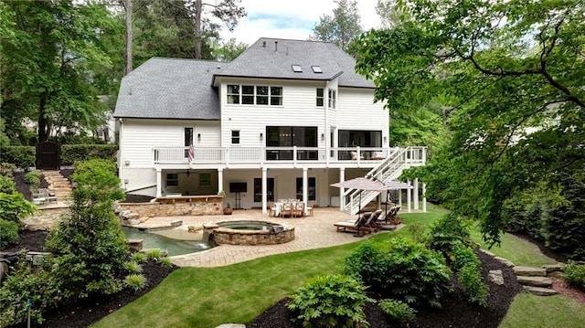 back of property featuring stairs, an in-ground hot tub, a patio area, and a shingled roof