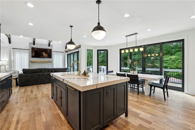 kitchen with healthy amount of natural light, light countertops, a sink, light wood-type flooring, and recessed lighting