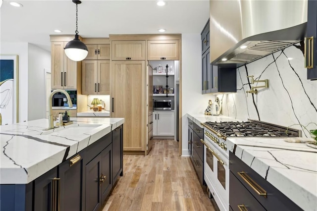 kitchen with wall chimney exhaust hood, high end white range oven, a sink, stainless steel microwave, and light wood-type flooring