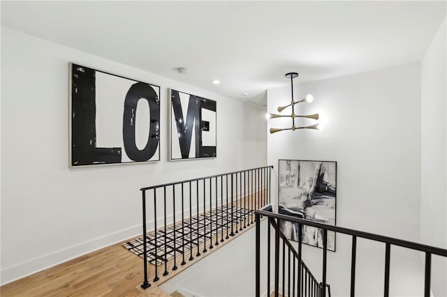 stairway with a chandelier, wood finished floors, recessed lighting, and baseboards