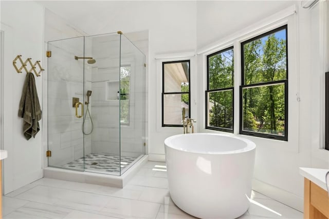full bath with healthy amount of natural light, vanity, a freestanding bath, and a stall shower