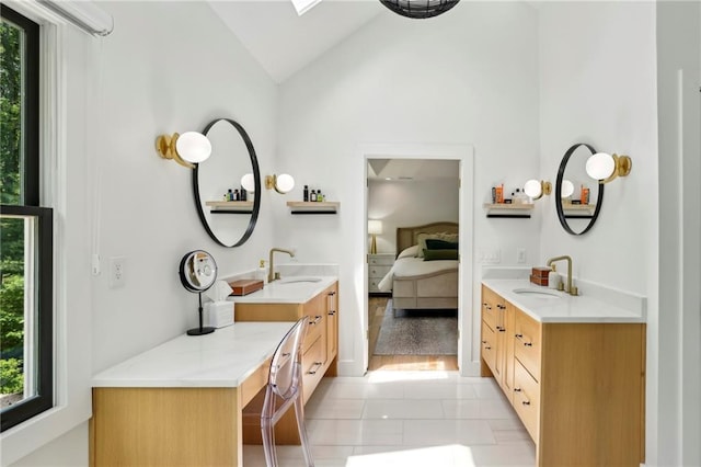 bathroom featuring vaulted ceiling, ensuite bath, and two vanities