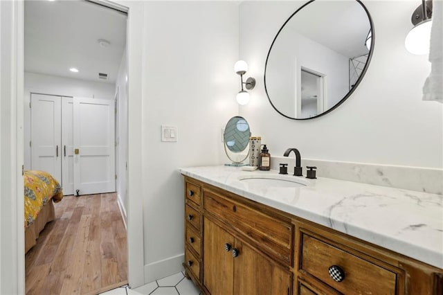 bathroom with baseboards, vanity, recessed lighting, and wood finished floors