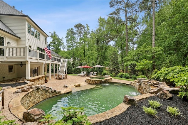 view of yard featuring stairs, a patio, a pool with connected hot tub, and a small pond