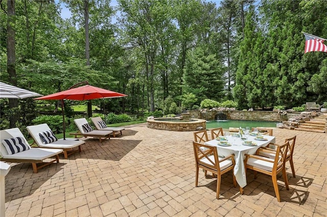view of patio / terrace featuring outdoor dining area and view of wooded area