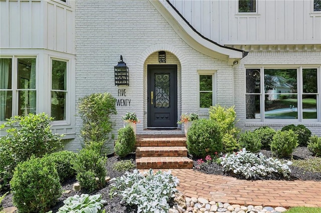 doorway to property with brick siding and board and batten siding