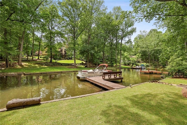 dock with a water view, a lawn, and view of wooded area