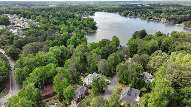 aerial view of property and surrounding area with a nearby body of water, a forest, and nearby suburban area
