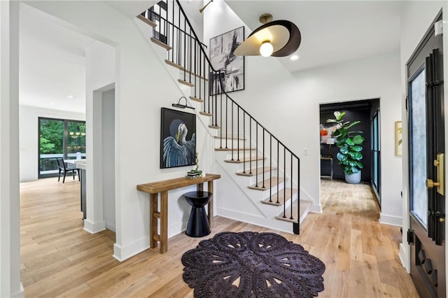 foyer with wood finished floors, stairway, and baseboards