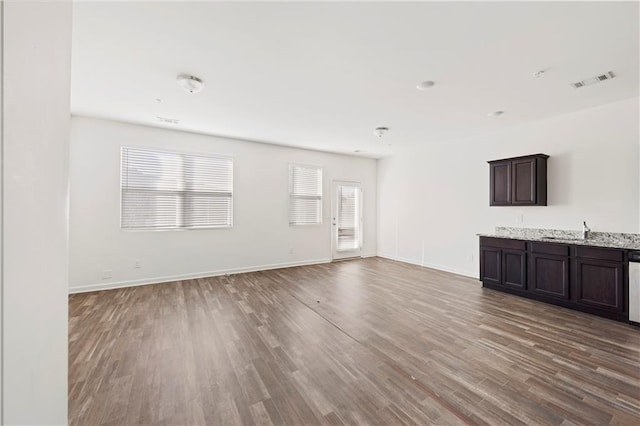 unfurnished living room featuring wood-type flooring and sink