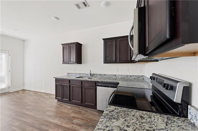 kitchen featuring stainless steel appliances, light stone counters, dark brown cabinetry, and sink