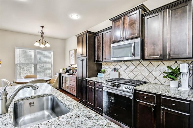 kitchen with sink, decorative light fixtures, an inviting chandelier, dark brown cabinets, and appliances with stainless steel finishes