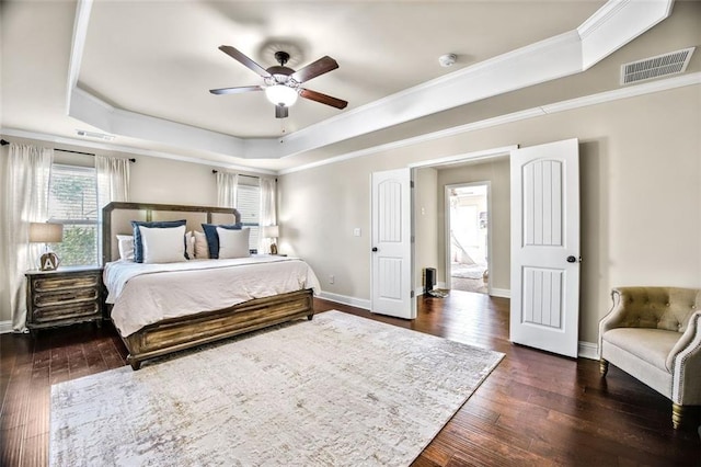 bedroom featuring ceiling fan, a tray ceiling, crown molding, and dark hardwood / wood-style flooring