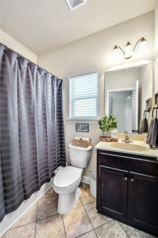 full bathroom with toilet, shower / bath combo with shower curtain, tile patterned floors, and vanity