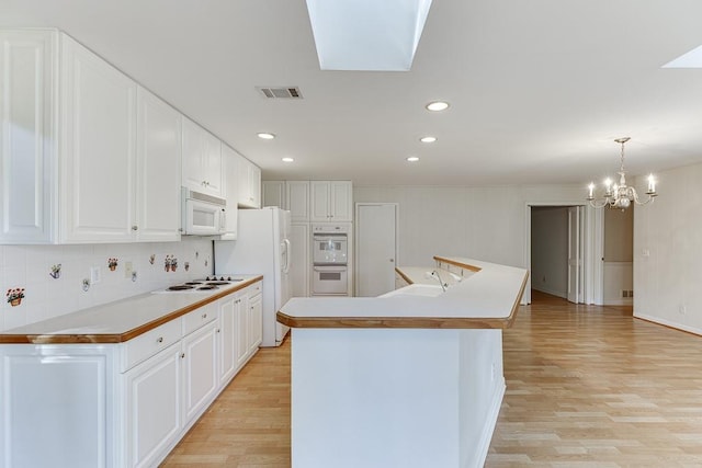 kitchen with an island with sink, pendant lighting, white appliances, and white cabinets