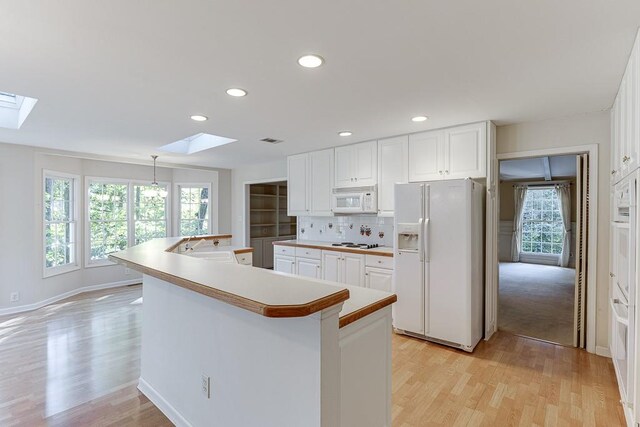 kitchen featuring white cabinetry, a skylight, and white appliances