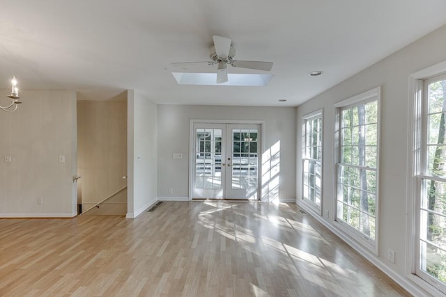 spare room featuring french doors, a healthy amount of sunlight, a skylight, and light wood-type flooring