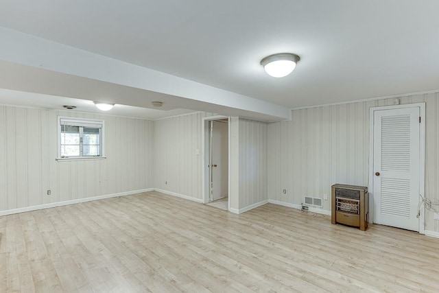 basement with heating unit, light hardwood / wood-style floors, and wood walls