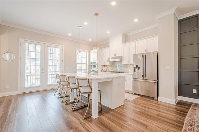 5005 Shay Town Ln, Peachtree Corners, GA 30092 - kitchen with under cabinet range hood, white cabinets, tasteful backsplash, light wood finished floors, and stainless steel appliances