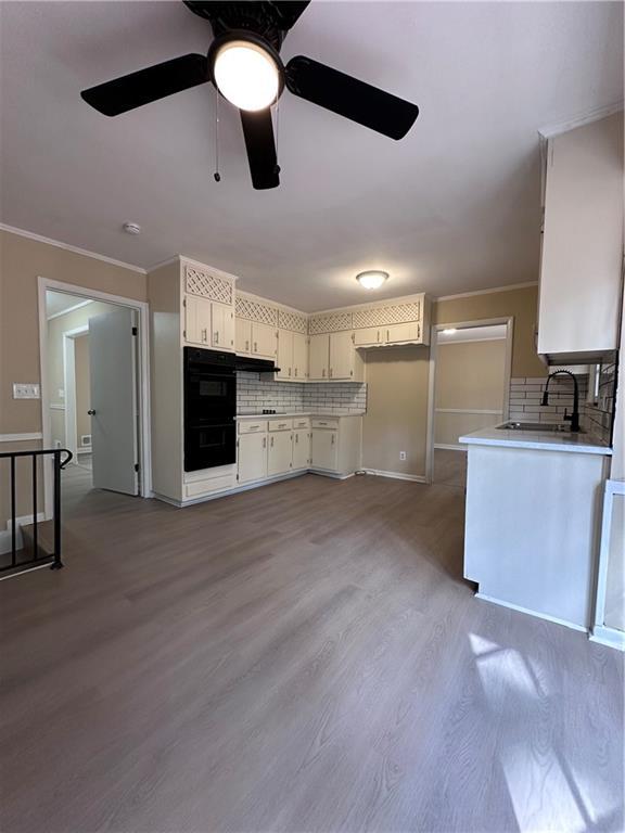 kitchen featuring wood finished floors, ornamental molding, a sink, and dobule oven black