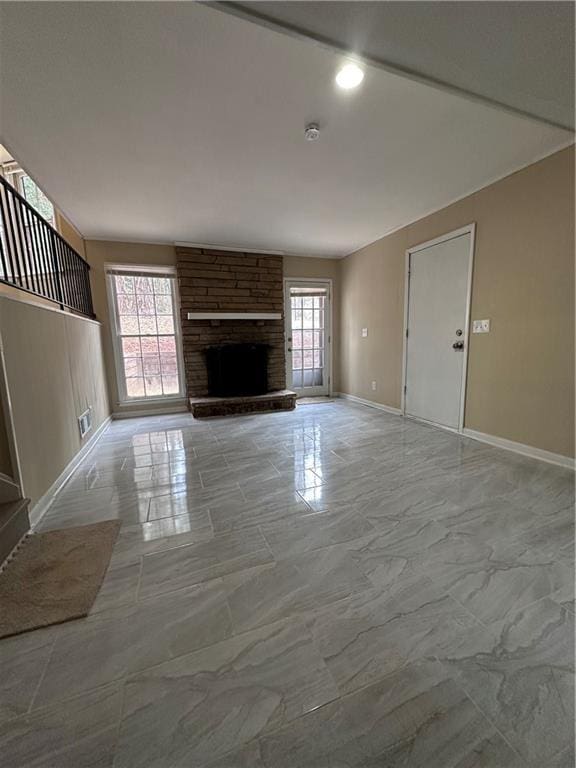 unfurnished living room featuring marble finish floor, a fireplace, a wealth of natural light, and baseboards