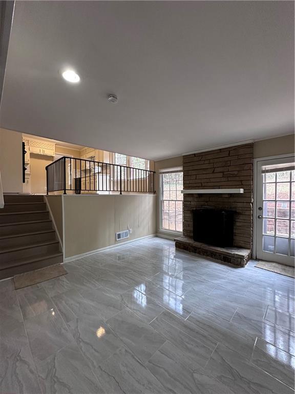 unfurnished living room featuring marble finish floor, stairway, a fireplace, and visible vents