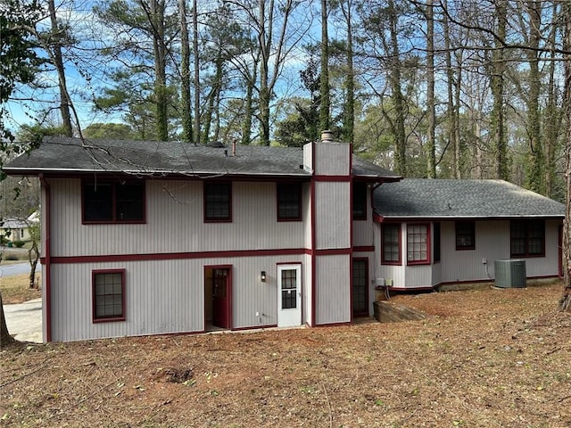 back of house featuring cooling unit and a chimney