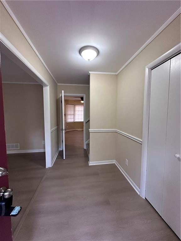 hall featuring crown molding, baseboards, and wood finished floors