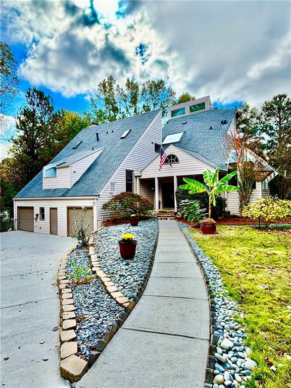 view of front of house featuring an attached garage, roof with shingles, and driveway