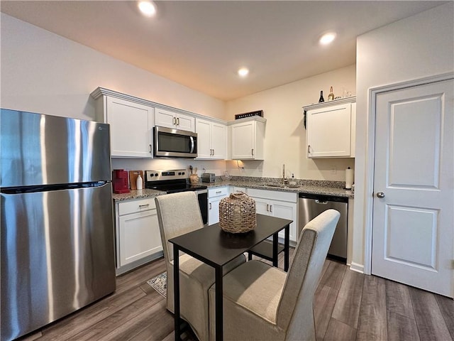 544 Magnolia Cir, Palmetto, GA 30268 - kitchen featuring appliances with stainless steel finishes, dark wood-type flooring, white cabinets, recessed lighting, and light stone counters