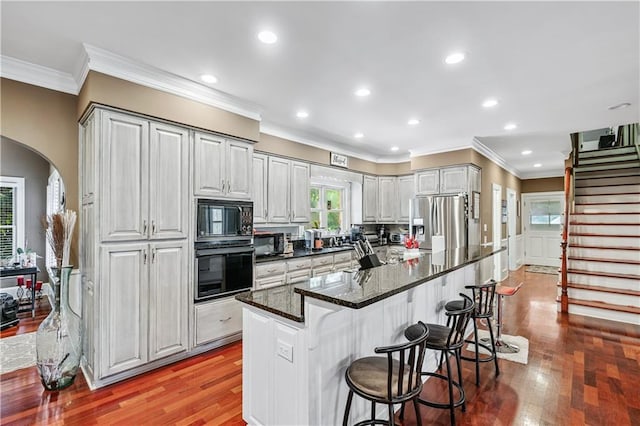 2012 Arbor Springs Way, Buford, GA 30519 - kitchen with black appliances, crown molding, wood finished floors, a breakfast bar, and recessed lighting