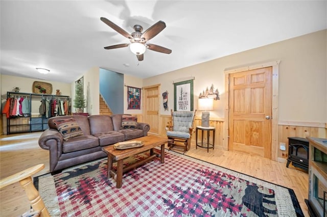 100 Julep Cir, Ellijay, GA 30540 - living room featuring a wood stove, wood finished floors, ceiling fan, stairway, and wainscoting