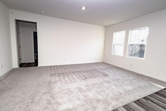 unfurnished room with carpet flooring, wood finished floors, and baseboards