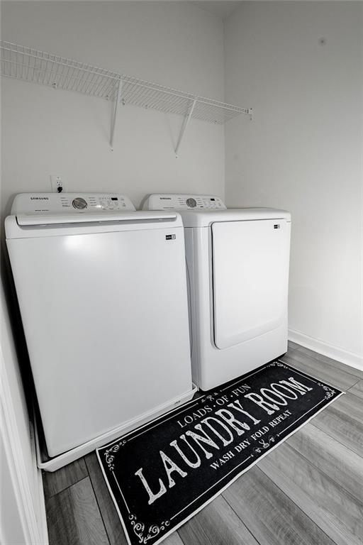 laundry room with laundry area, baseboards, washer and clothes dryer, and wood finished floors