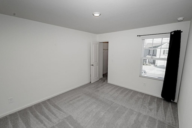 unfurnished room featuring carpet and baseboards