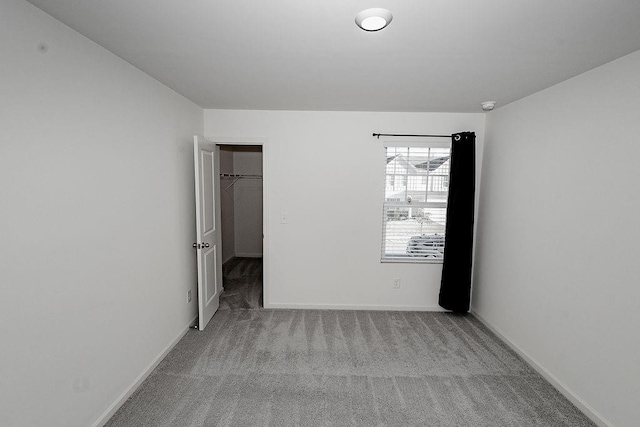 unfurnished bedroom with carpet floors, baseboards, and a walk in closet