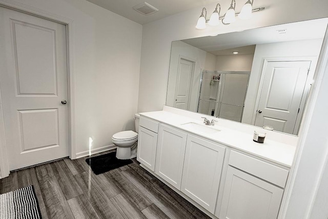 full bath featuring toilet, wood finished floors, vanity, visible vents, and a shower stall