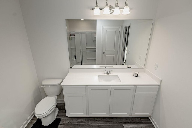 bathroom with wood finished floors, vanity, toilet, and baseboards