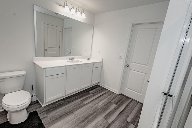 bathroom featuring baseboards, vanity, toilet, and wood finished floors