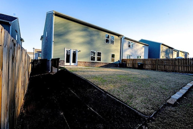 back of house with a fenced backyard and brick siding